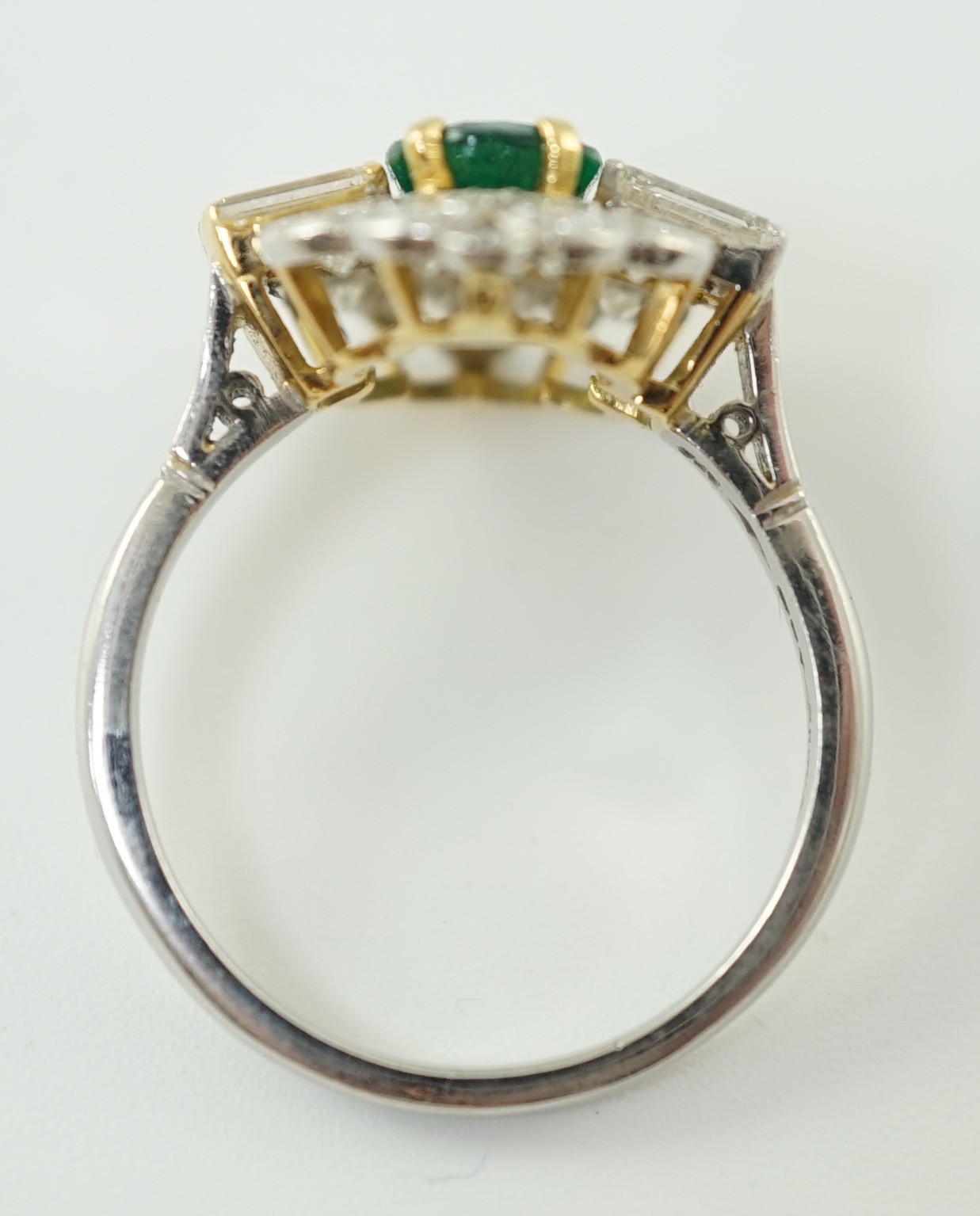 A modern platinum, oval cut emerald and baguette and round cut diamond set cluster ring